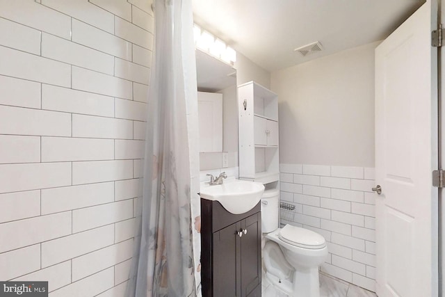 bathroom featuring walk in shower, vanity, tile walls, and toilet