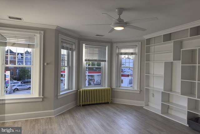 spare room featuring ceiling fan, radiator heating unit, hardwood / wood-style flooring, and ornamental molding