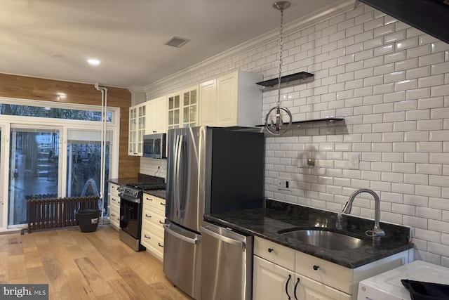 kitchen featuring backsplash, dark stone counters, white cabinets, sink, and appliances with stainless steel finishes