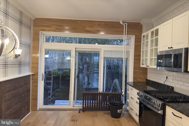 kitchen with white cabinets, black range with gas stovetop, crown molding, and dark stone counters