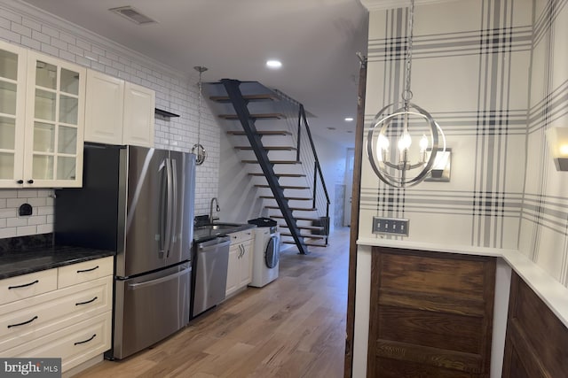 kitchen with decorative backsplash, stainless steel appliances, sink, decorative light fixtures, and washer / clothes dryer