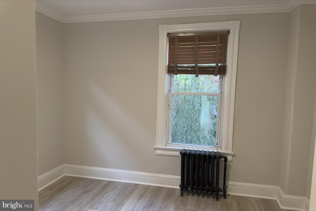 empty room with radiator heating unit, light wood-type flooring, and crown molding