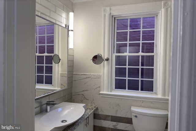 bathroom with vanity, tile walls, and toilet