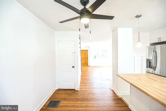 corridor featuring baseboards, visible vents, and wood finished floors