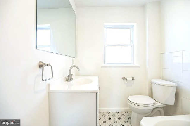 bathroom with baseboards, a wealth of natural light, toilet, and vanity