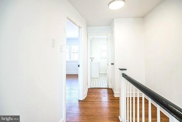 hall with an upstairs landing, wood finished floors, and baseboards