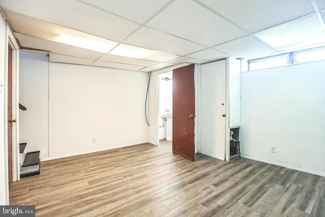 basement with a paneled ceiling and hardwood / wood-style flooring