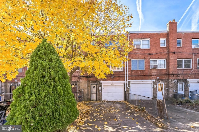 view of front of house featuring driveway, fence, brick siding, and a garage