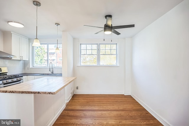 kitchen featuring wood finished floors, gas range, a sink, white cabinetry, and a ceiling fan