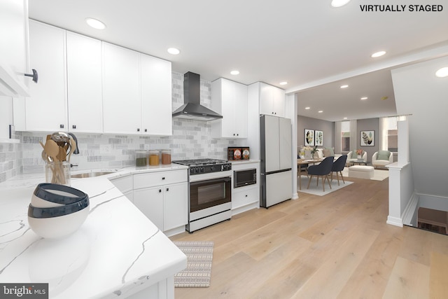 kitchen featuring white appliances, wall chimney exhaust hood, light wood-type flooring, and white cabinets