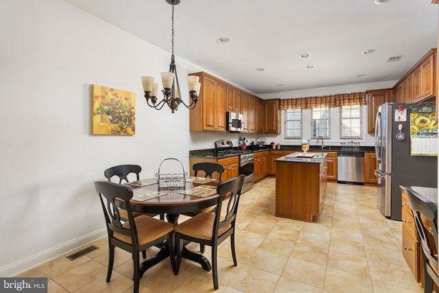 kitchen with sink, a chandelier, light tile patterned floors, appliances with stainless steel finishes, and a kitchen island