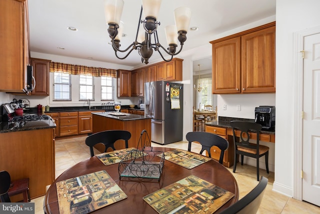 kitchen featuring sink, a chandelier, a center island, light tile patterned floors, and appliances with stainless steel finishes