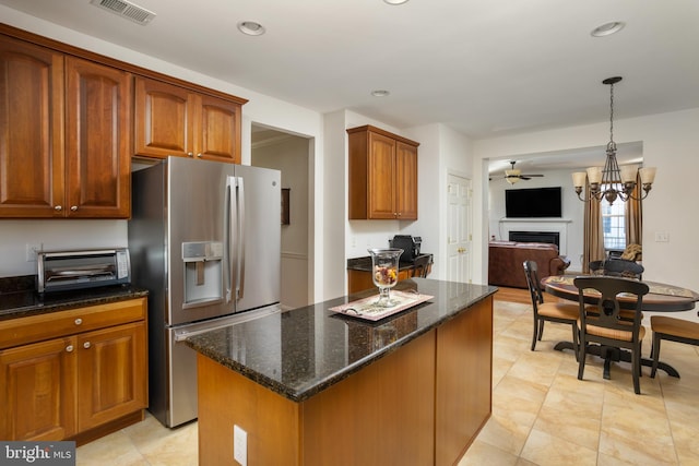 kitchen featuring dark stone countertops, decorative light fixtures, stainless steel fridge, and ceiling fan