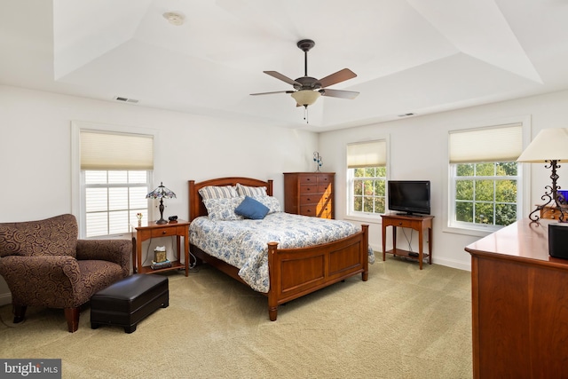 carpeted bedroom featuring ceiling fan and a raised ceiling