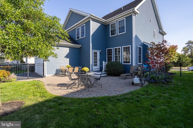 back of property with a yard and a patio