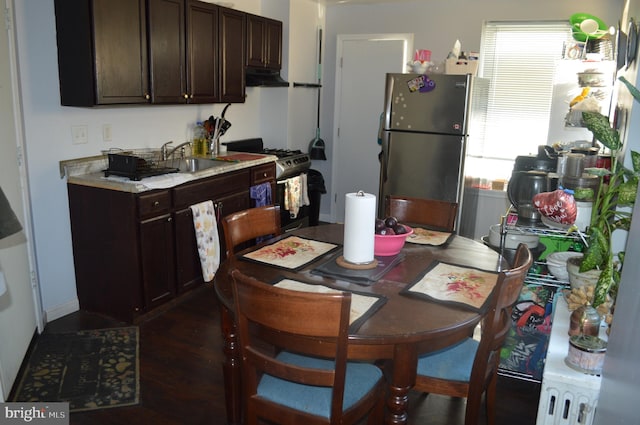 kitchen featuring dark wood-type flooring, sink, dark brown cabinetry, black gas range oven, and stainless steel refrigerator