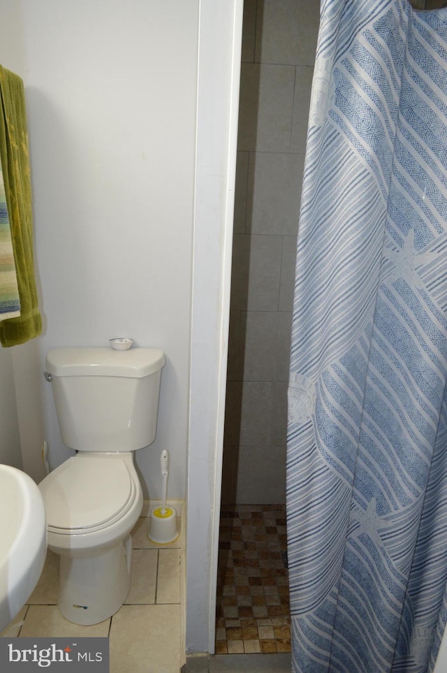 bathroom with toilet, tile patterned floors, and walk in shower