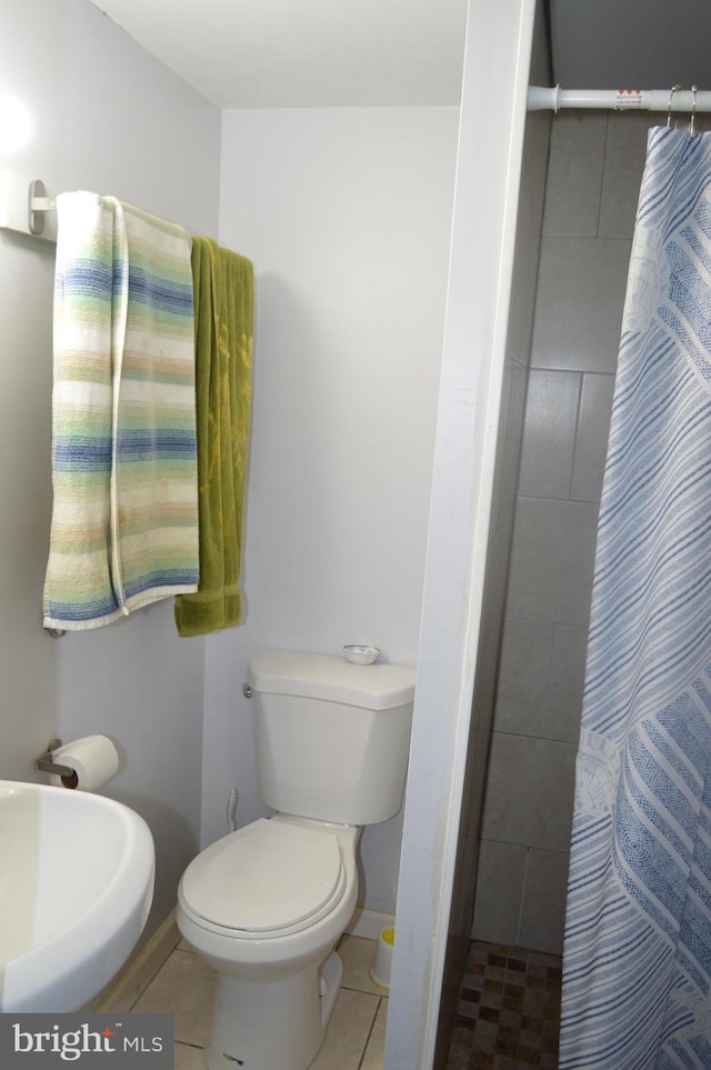 bathroom with tile patterned floors, sink, curtained shower, and toilet