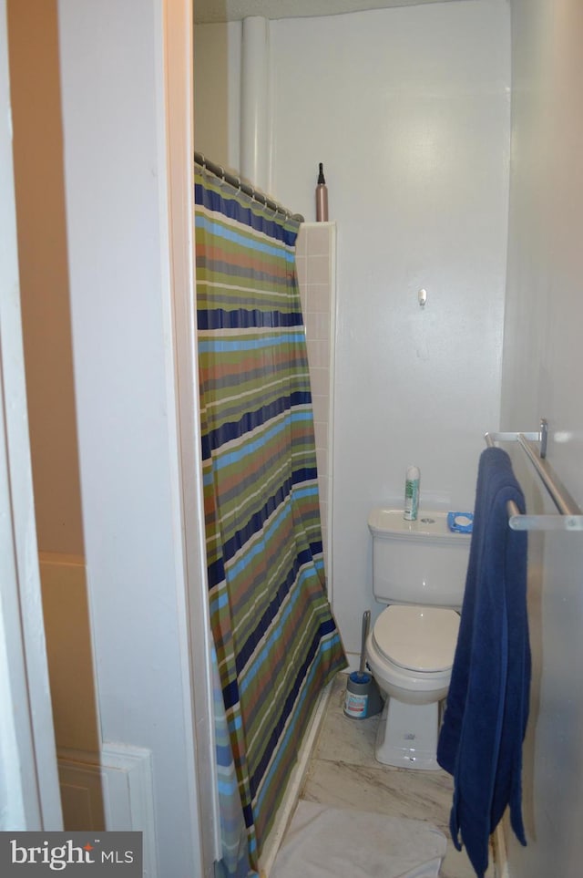 bathroom featuring a shower with shower curtain and toilet