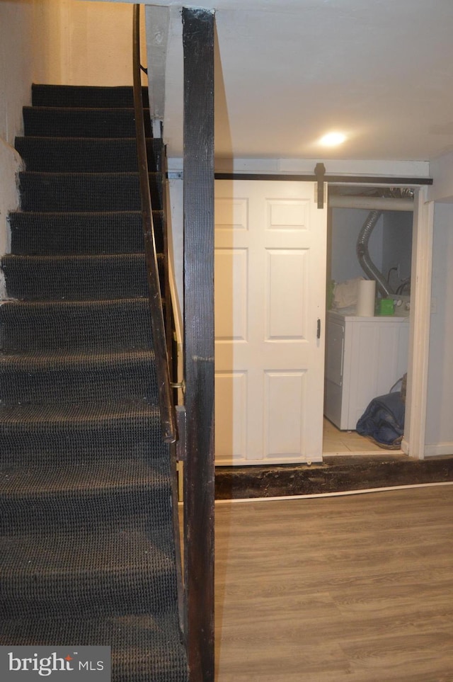 staircase with independent washer and dryer, a barn door, and hardwood / wood-style floors