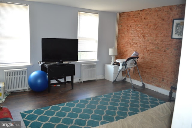 interior space with brick wall, dark wood-type flooring, and radiator