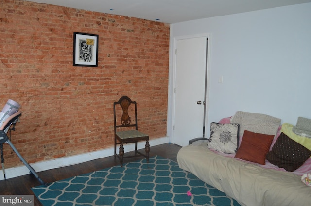 living room with brick wall and dark wood-type flooring