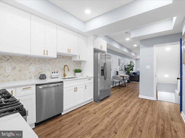 kitchen with stainless steel appliances, sink, light hardwood / wood-style flooring, and white cabinetry