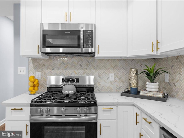 kitchen with decorative backsplash, white cabinets, appliances with stainless steel finishes, and light stone counters