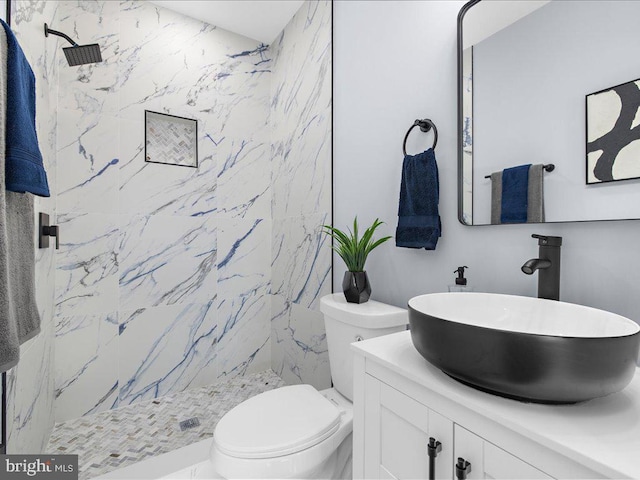 bathroom with vanity, toilet, and tiled shower