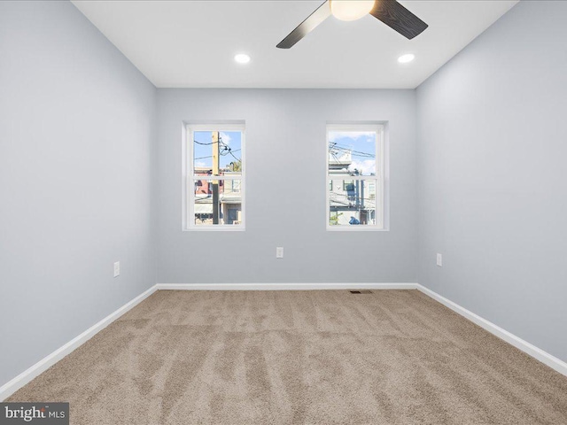 carpeted spare room featuring ceiling fan and a wealth of natural light