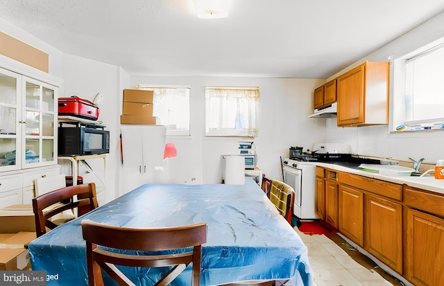 kitchen with sink, white gas range oven, and light tile patterned floors