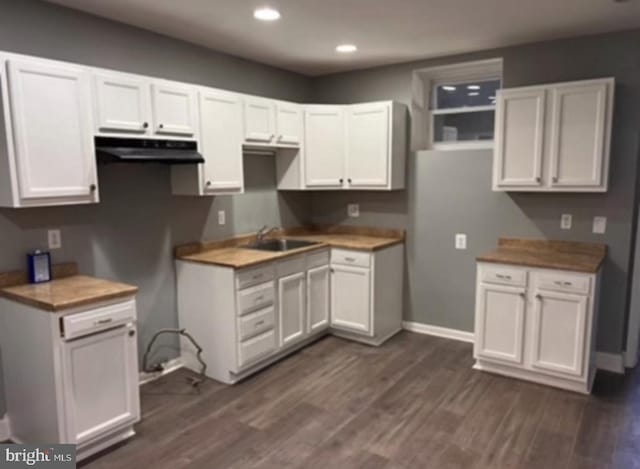 kitchen with dark hardwood / wood-style flooring, sink, wood counters, and white cabinets