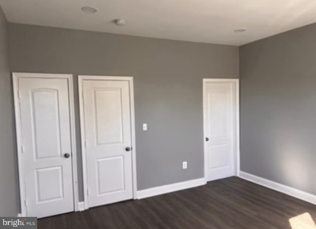 unfurnished bedroom with dark wood-type flooring