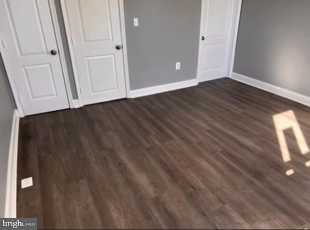 unfurnished bedroom with a closet and dark hardwood / wood-style flooring