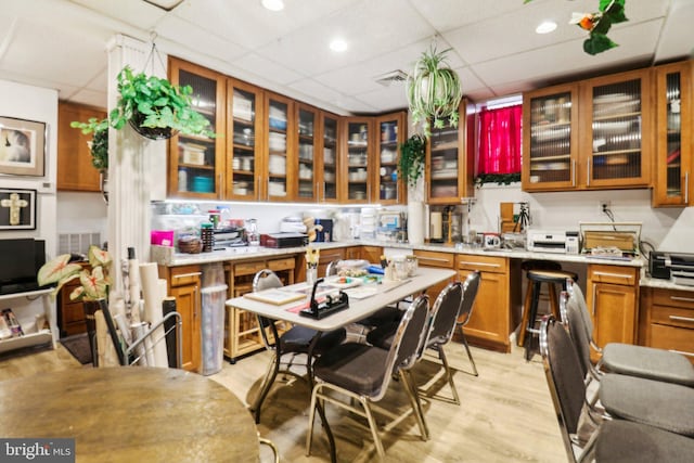 3536 Minnesota Ave SE, Washington, DC 20019 - kitchen with brown cabinets, a drop ceiling, light countertops, glass insert cabinets, and light wood-style floors