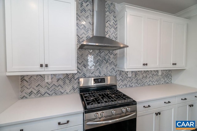 kitchen with white cabinets, backsplash, gas stove, and wall chimney range hood