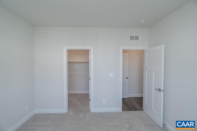 unfurnished bedroom featuring a closet, a walk in closet, and carpet flooring