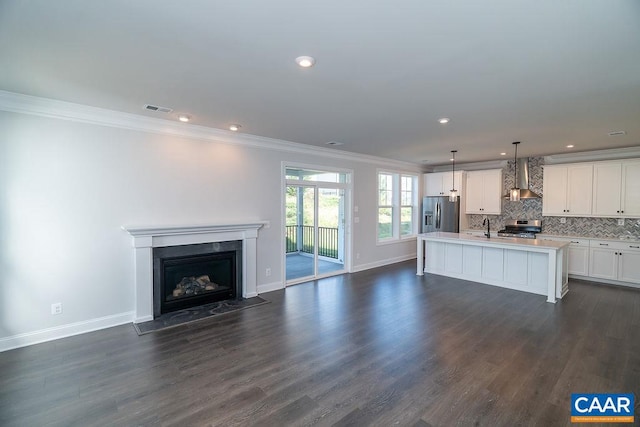 kitchen with decorative light fixtures, appliances with stainless steel finishes, dark hardwood / wood-style floors, and a kitchen island with sink