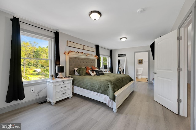 bedroom featuring light wood-type flooring and connected bathroom