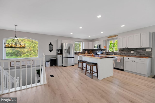 kitchen with stainless steel appliances, light hardwood / wood-style floors, and white cabinetry