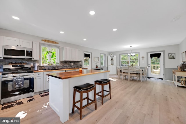 kitchen featuring appliances with stainless steel finishes, light wood-type flooring, white cabinetry, and butcher block counters