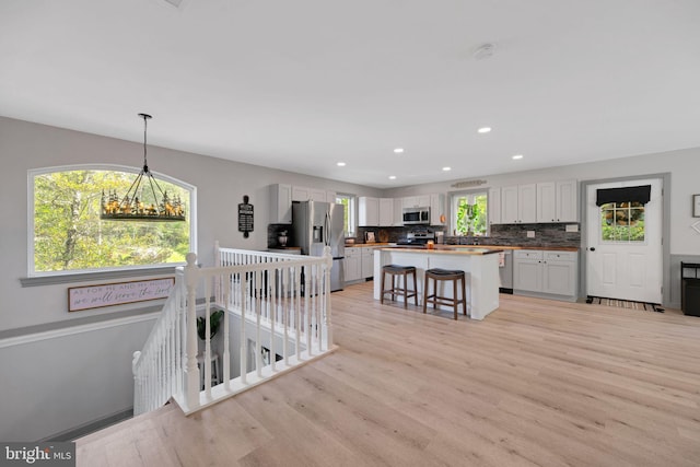 kitchen with pendant lighting, light hardwood / wood-style flooring, a breakfast bar, stainless steel appliances, and a center island