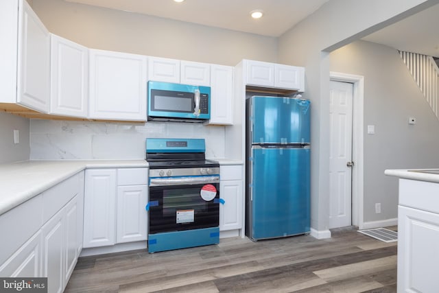 kitchen with light hardwood / wood-style flooring, appliances with stainless steel finishes, and white cabinetry