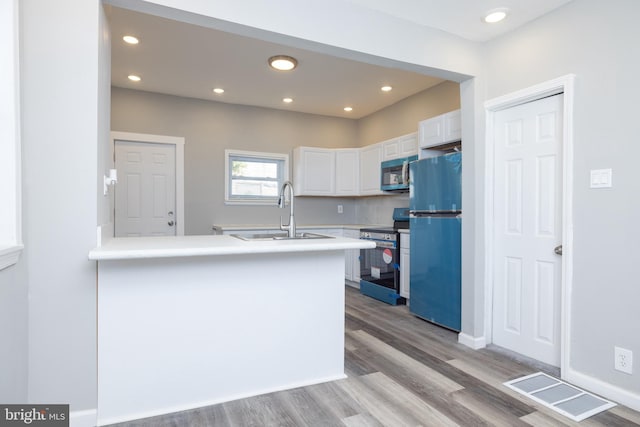 kitchen featuring light hardwood / wood-style floors, sink, stainless steel appliances, kitchen peninsula, and white cabinetry