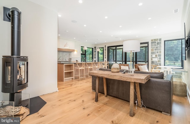 living room with a wealth of natural light, light hardwood / wood-style floors, and crown molding