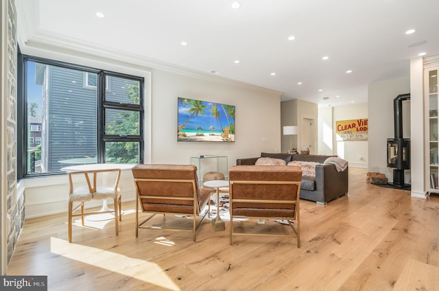 living room with light wood-type flooring, ornamental molding, and a wood stove