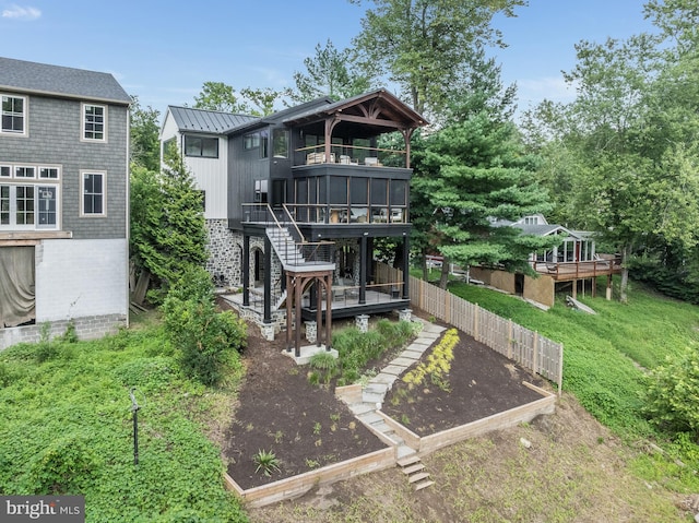 rear view of property featuring a wooden deck and a lawn