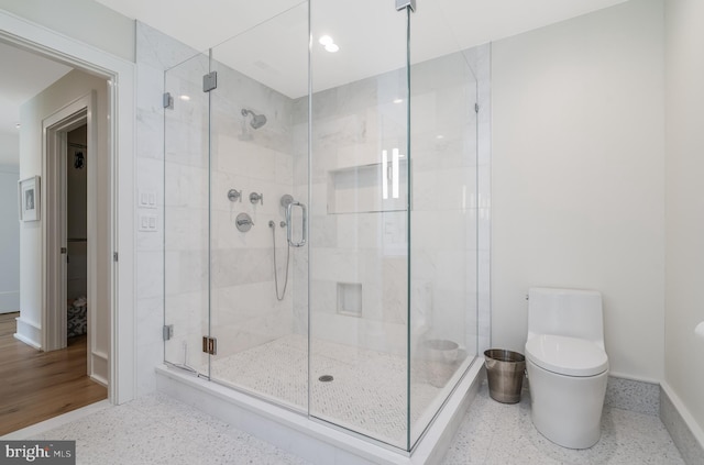 bathroom featuring a shower with shower door and toilet