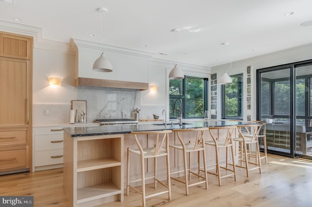 kitchen with an island with sink, a wealth of natural light, hanging light fixtures, and sink