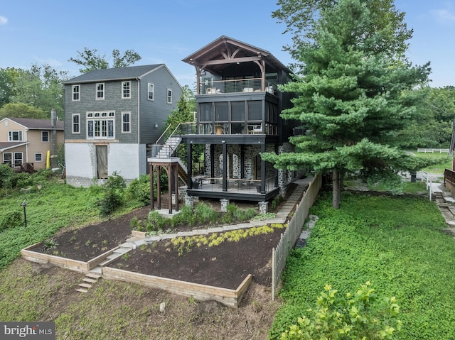 rear view of property with a sunroom, a deck, and a yard